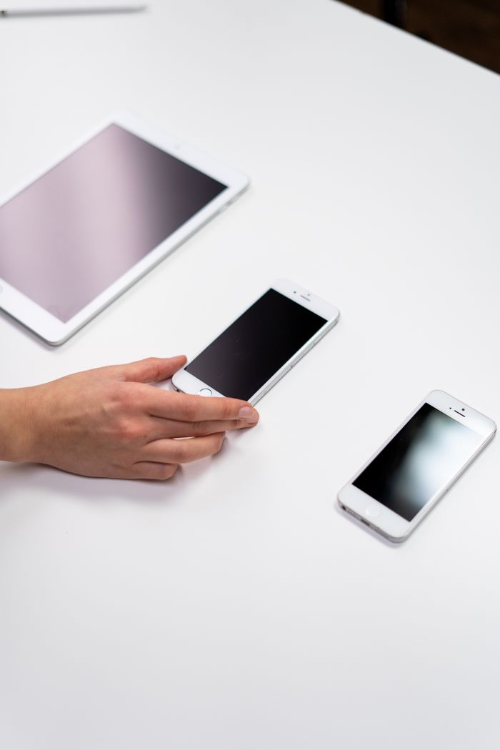 who-we-are A top-down view of a minimalist setup with a tablet and smartphones arranged on a white surface.